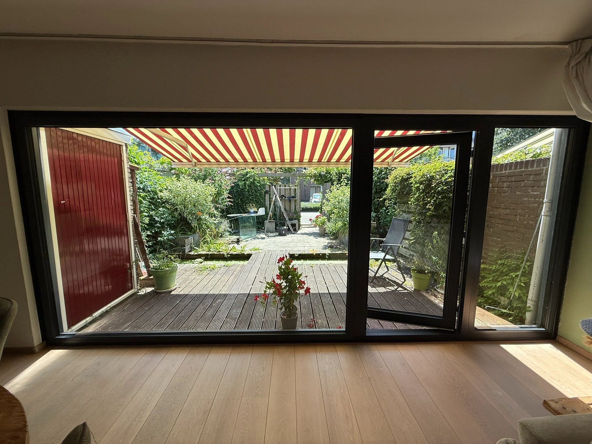 Uitzicht vanuit de woonkamer door een GEALAN S 9000 NL schuifpui naar het terras en de tuin