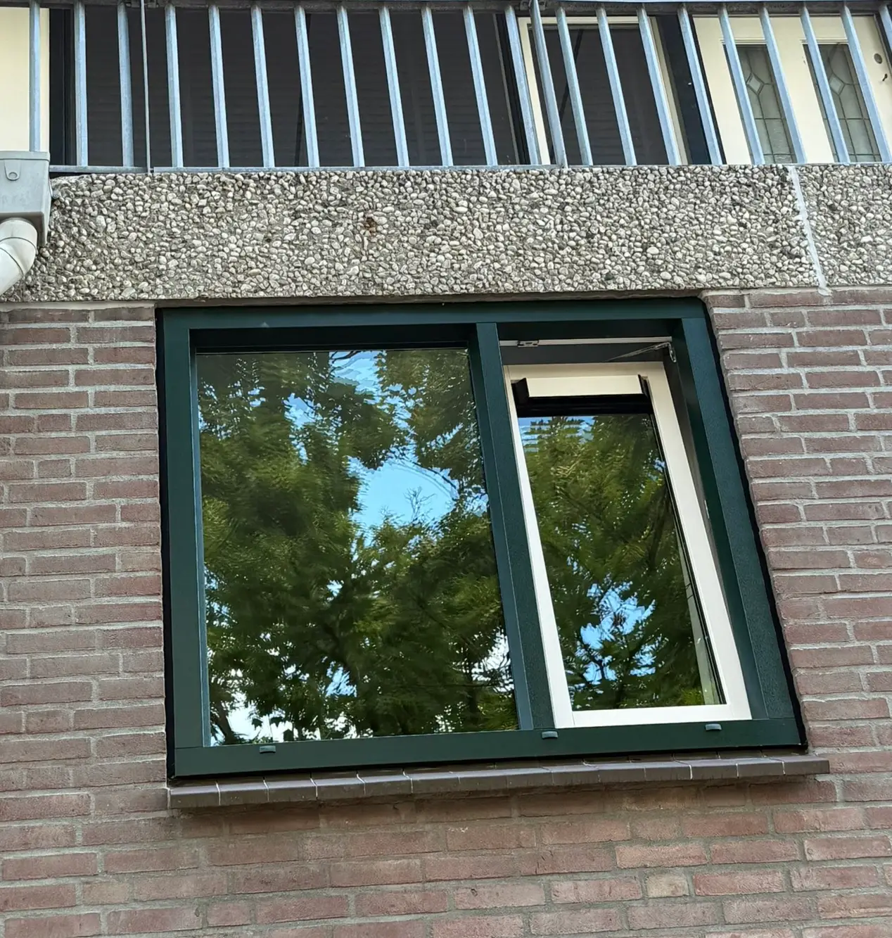 Kömmerling K-Vision kozijn in donkergroen, door Fenstermacher geplaatst in een bakstenen gevel