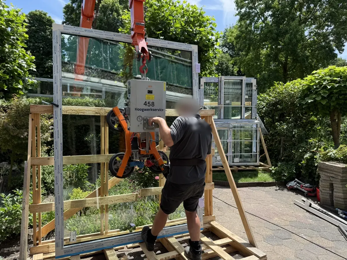 Een grote ruit wordt met een vacuüm-glaszuiger in het kozijn gezet